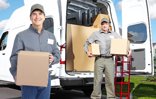 Removal team carrying furniture through a London flat staircase